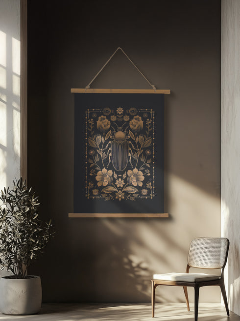 A symmetrical wall tapestry featuring a large scarab beetle in antique bronze tones surrounded by detailed flowers and botanical elements on a black background, mounted on wooden dowels with twine.